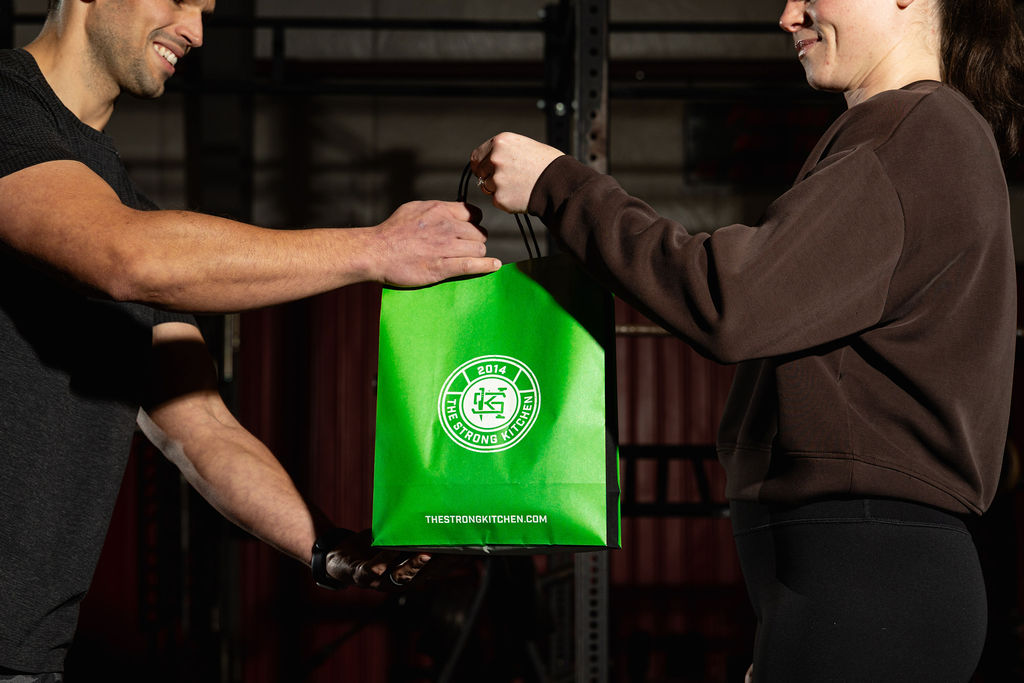 A Strong Kitchen bag handed to a customer at the gym